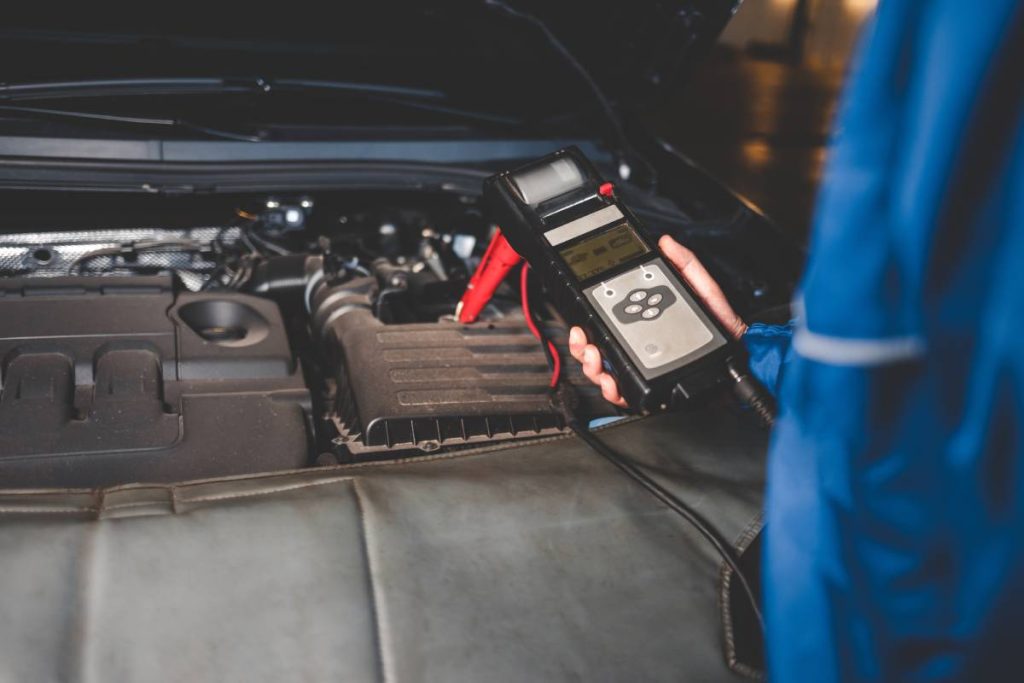 Auto mechanic checks car battery status. Checking the vehicle electrical system concept