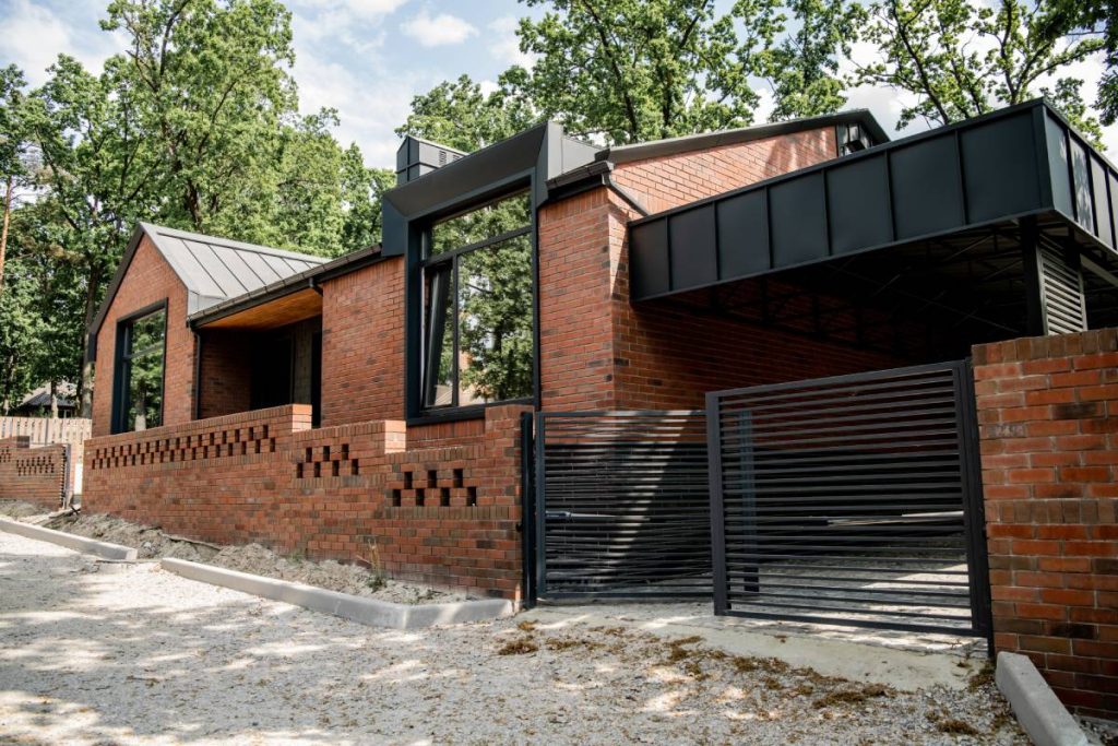 housing trends, brick contemporary house with metal gates and brick fence